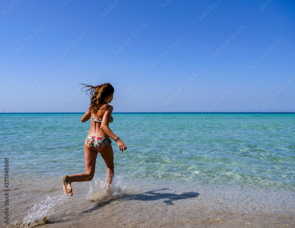 Slim and athletic girl in a colourful bikini jumping into the crystal clear water of a beautiful beach -vacation-fitness-wellness Slim and athletic girl in a colourful bikini jumping into the crystal clear water of a beautiful beach -vacation-fitness-wellness