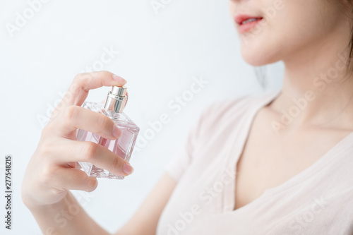 woman is spraying perfume at the neck.
