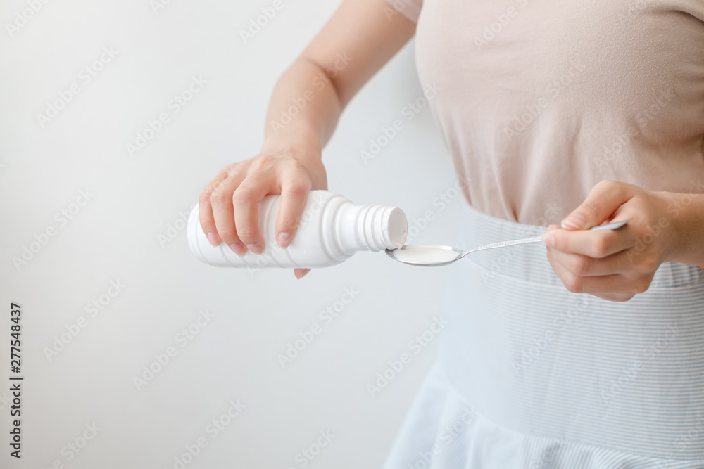 Women pouring drugs or antacids in their hands because of the food from their hands to the bottle. Concepts of health care, people and medicine Women pouring drugs or antacids in their hands because of the food from their hands to the bottle. Concepts of health care, people and medicine
