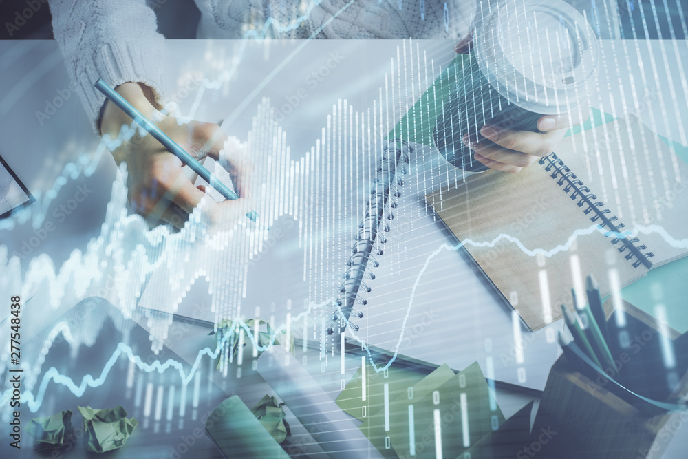 Fototapeta premium Financial forex graph displayed on hands taking notes background. Concept of research. Multi exposure