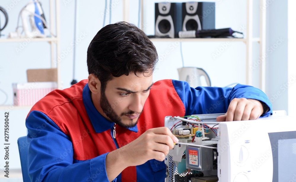 Young repairman fixing and repairing microwave oven Young repairman fixing and repairing microwave oven