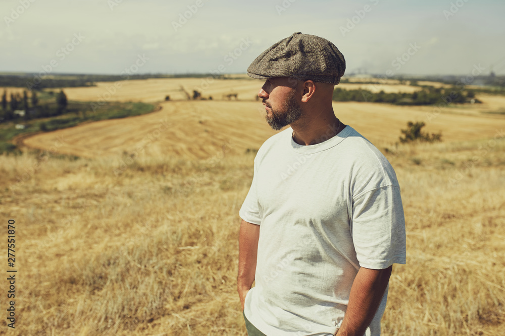 man in a t-shirt and a cap on the background of cereal fields