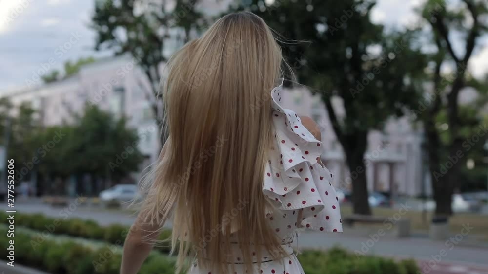 Happy woman in dress throwing her beautiful blonde hair at summer city alley, slowmotion Happy woman in dress throwing her beautiful blonde hair at summer city alley, slowmotion
