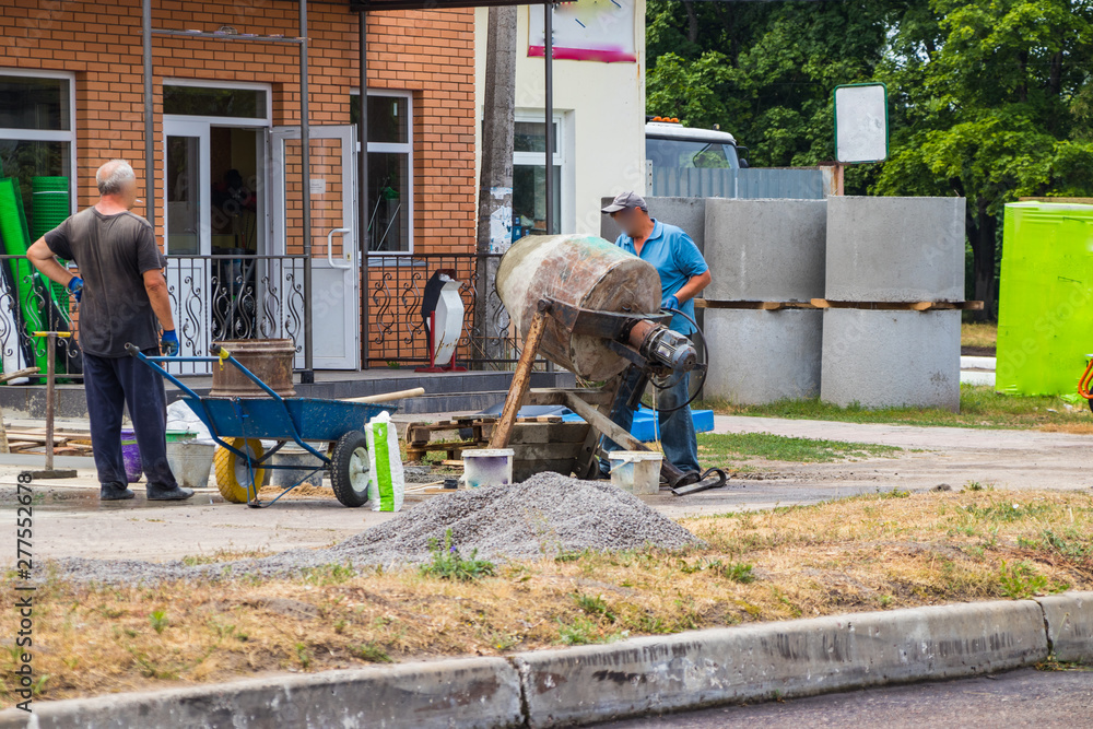 Builders are kneading a concrete solution with a concrete mixer. Builders are kneading a concrete solution with a concrete mixer.