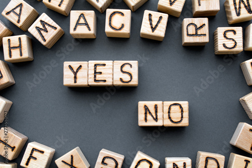 words yes no composed of wooden cubes with letters, concept of choice, scattered around the cubes random letters, top view on gray background