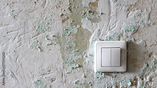 The white switch on the old plastered wall