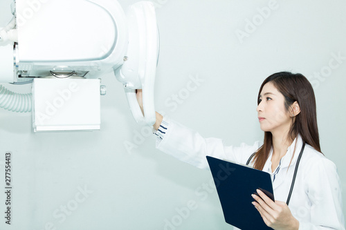 Beautiful Radiologist woman doctor 1st time setting X-ray Machine with Operation Manual in her left hand.