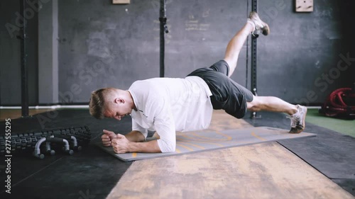 High performance triathlon or marathon exercises. Man in good fit does plank alternating leg lifts for improving sports training. Available exercises for office workers. Intermediate no equipment