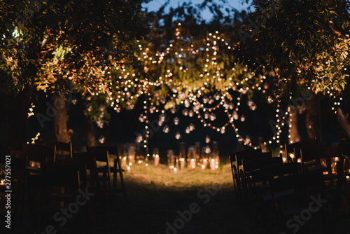 Coziness and style. Modern event design. Lounge zone and european traditional wedding ceremony decoration outdoors in the evening, decorated with candles and lights.