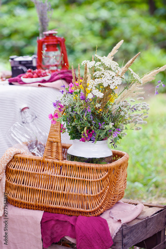 Summer picnic on nature, with a delicious chocolate cake, compote, berries, wild flowers