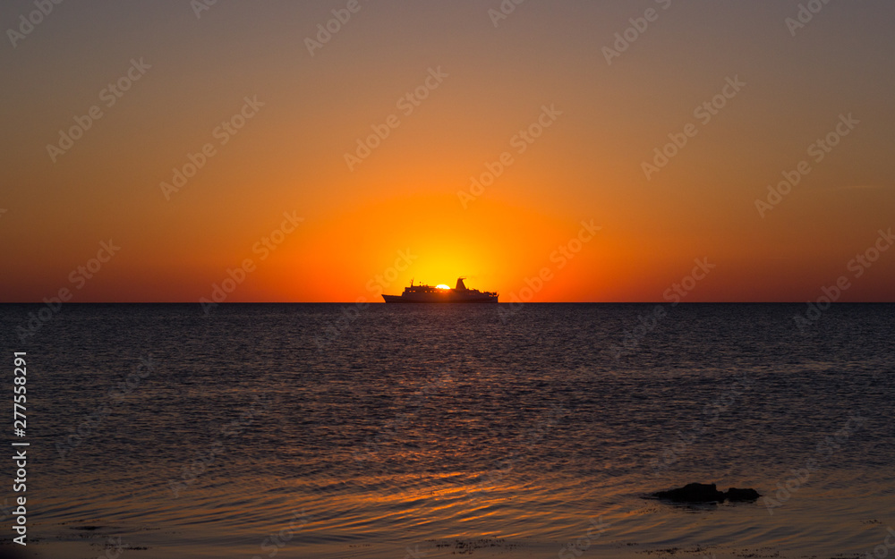 Silhouette of a tourist ship at sunset