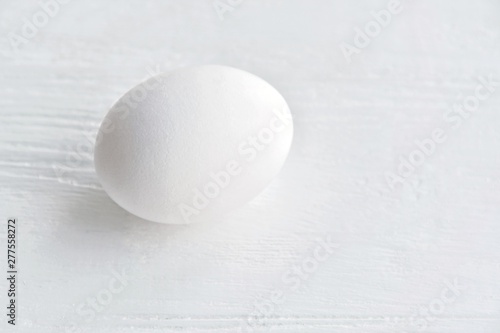 White chicken egg with selective focus on blurred textured gray background. Fresh organic fragility egg on neutral backdrop  soft focus. Ingredient for healthy diet breakfast. Easter symbol 