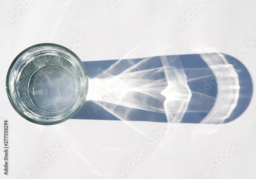 Water glass with strong shadows on white background