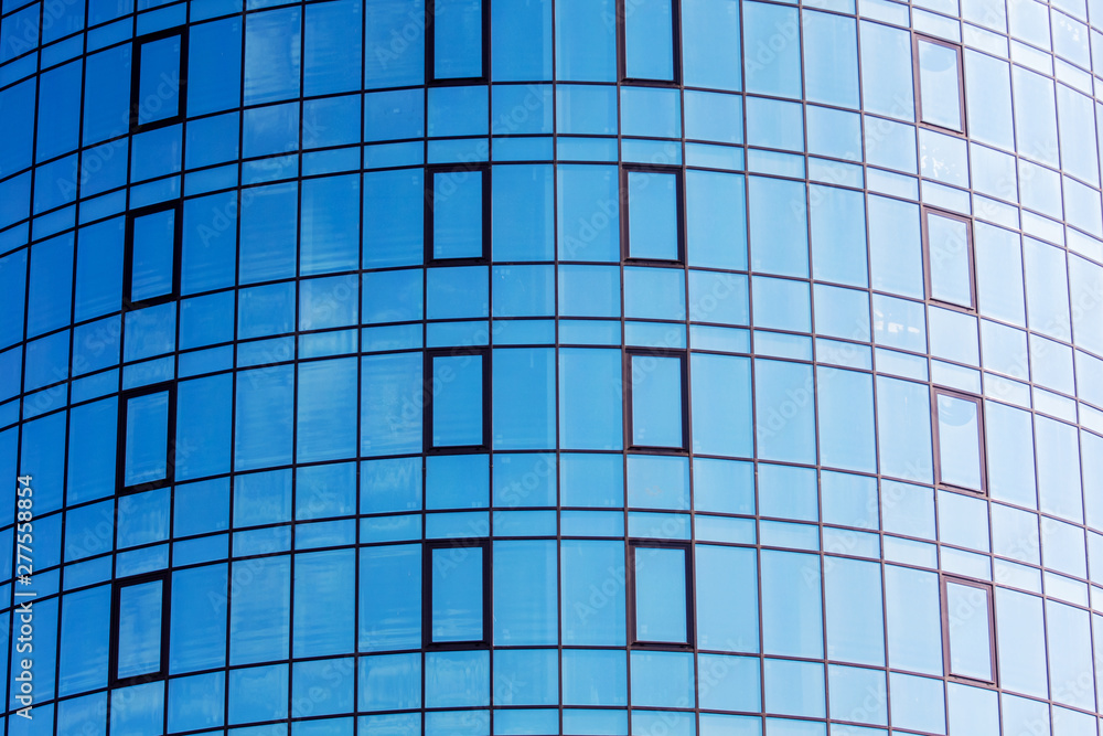 A fragment of a modern house with large windows that displays a blue sky. Modern architecture using glass constructions_ A fragment of a modern house with large windows that displays a blue sky. Modern architecture using glass constructions_