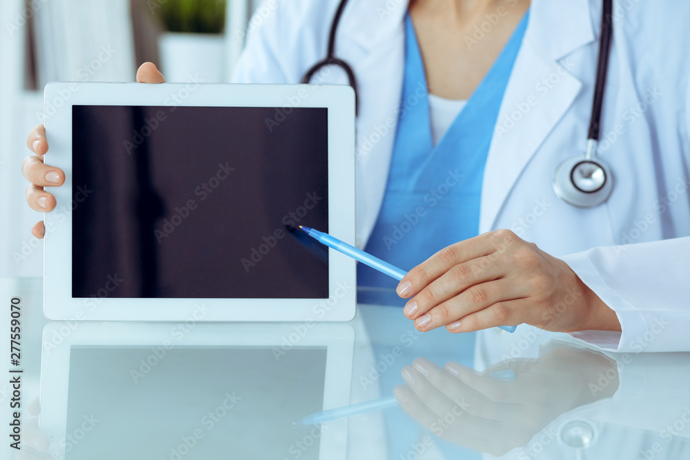Female doctor using tablet computer while sitting at the workplace, close-up of hands. Medicine, healthcare and help concept Female doctor using tablet computer while sitting at the workplace, close-up of hands. Medicine, healthcare and help concept