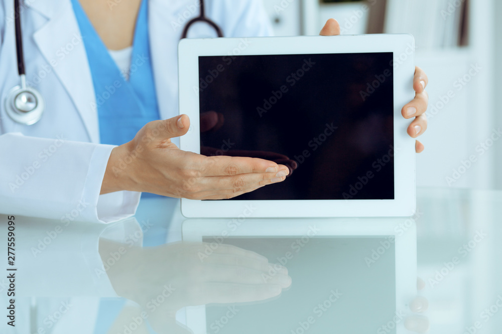 Female doctor using tablet computer while sitting at the workplace, close-up of hands. Medicine, healthcare and help concept Female doctor using tablet computer while sitting at the workplace, close-up of hands. Medicine, healthcare and help concept