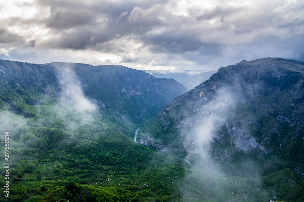 Montenegro, Aerial perspective view over endless green tara river canyon nature landscape with some clouds from summit of mount curevac in durmitor national park near zabljak Montenegro, Aerial perspective view over endless green tara river canyon nature landscape with some clouds from summit of mount curevac in durmitor national park near zabljak