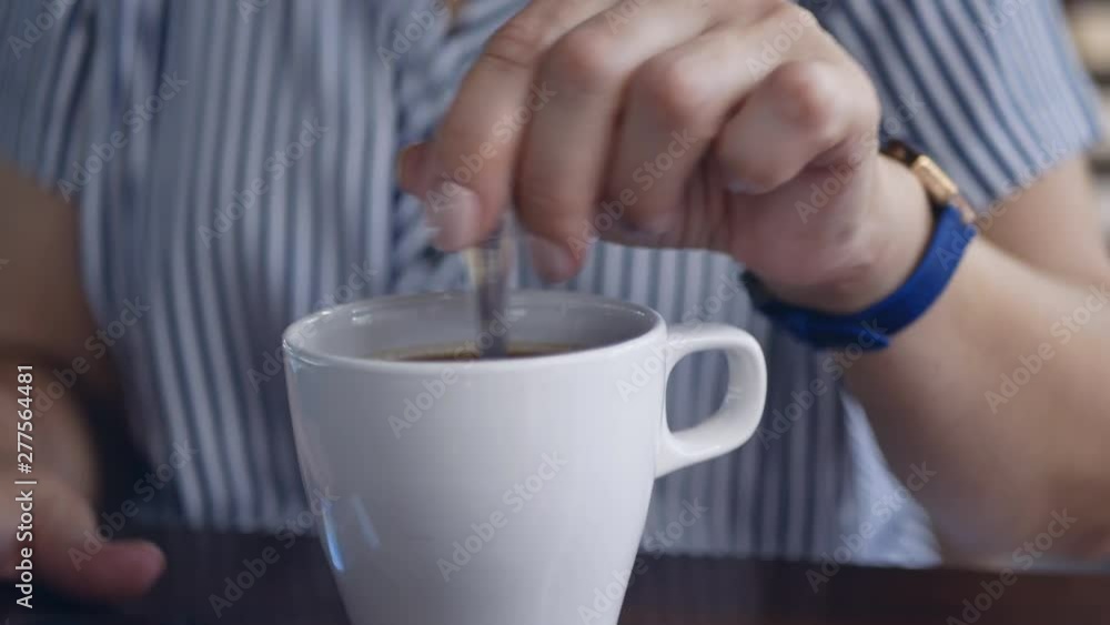 woman's hand stirs sugar in a cup of coffee woman's hand stirs sugar in a cup of coffee
