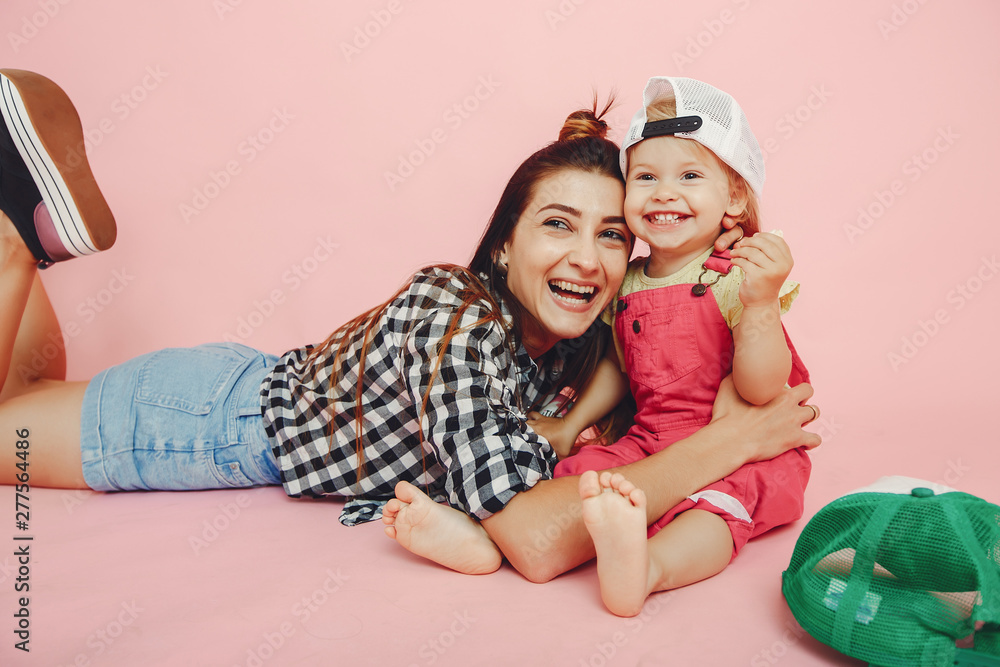 Stylish mother in a shirt and shorts. Little girl in a fashion clothes. Family have fun in a studio Stylish mother in a shirt and shorts. Little girl in a fashion clothes. Family have fun in a studio