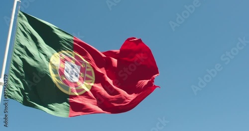 Flag Of Portugal waving on the wind, on the sunny day against bright blue sky, slow motion close up shot photo