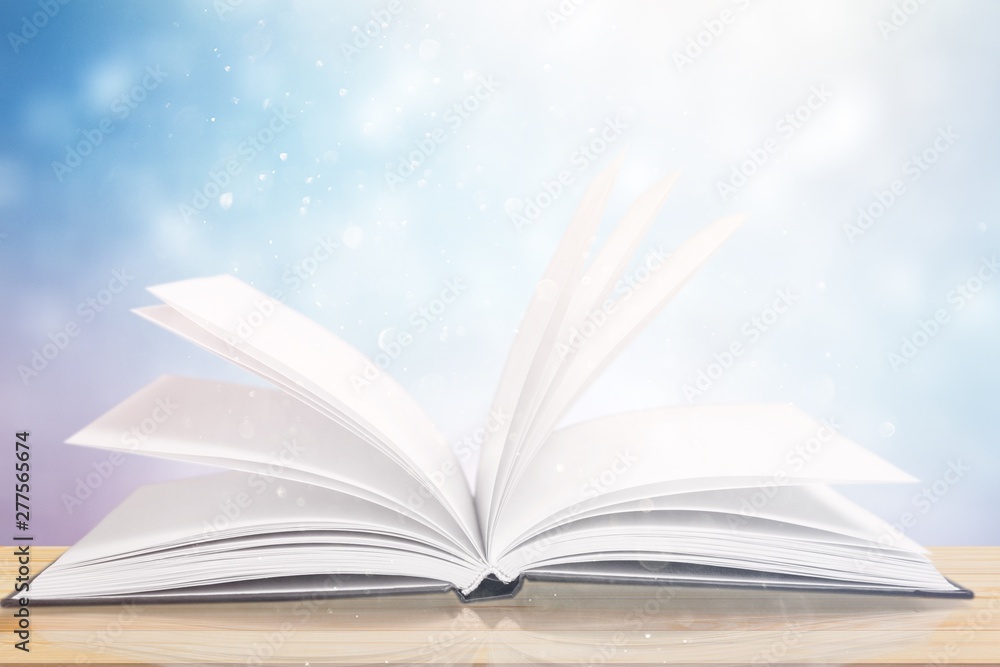 Open book on old wooden table on sky background sunlit Open book on old wooden table on sky background sunlit