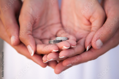 Bride and groom holding wedding rings on their palms during ceremony
