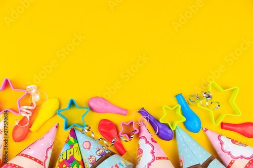 Birthday party caps, balloon and stars on yellow background. Colorful celebration background with various party.