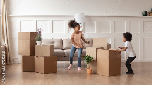 Happy active african kids playing with boxes on moving day
