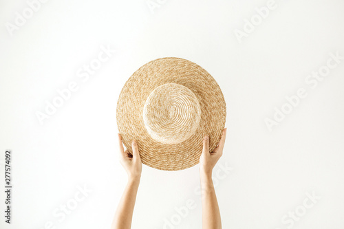 Minimalistic summer and travel concept. Woman's hands holding a straw yellow hat. Front view.