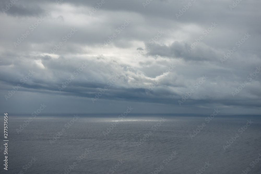 Sun illuminating empty sea through gap in clouds