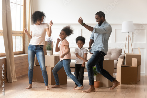 Happy african american parents and children dancing celebrating moving day photo