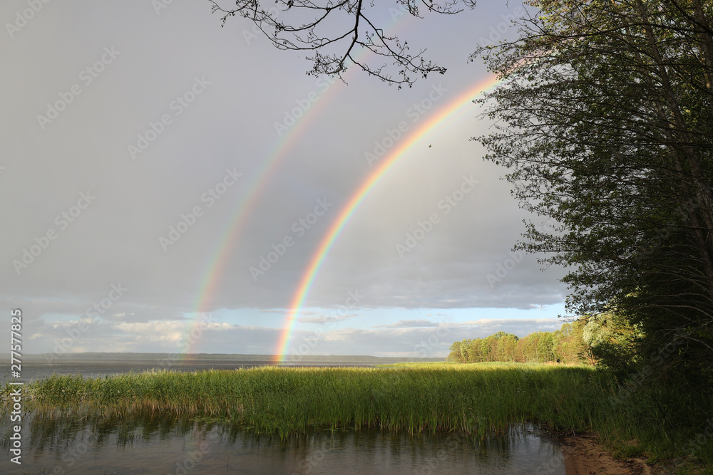 Double rainbow over the lake in cloudy weather Double rainbow over the lake in cloudy weather