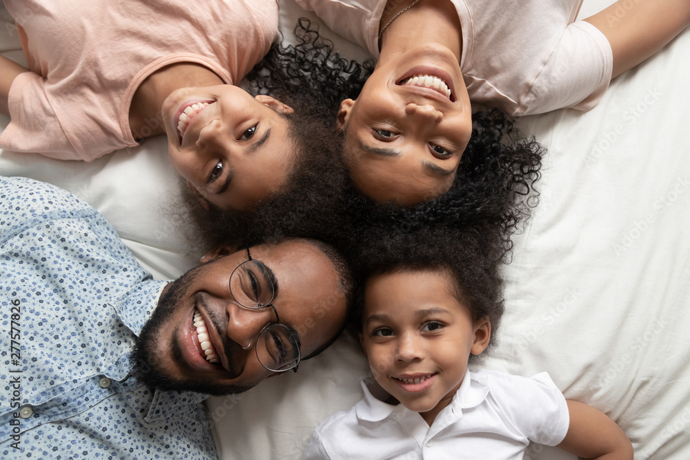 Happy african family looking at camera on bed, top view - obrazy, fototapety, plakaty 