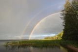 Double rainbow over the lake in cloudy weather