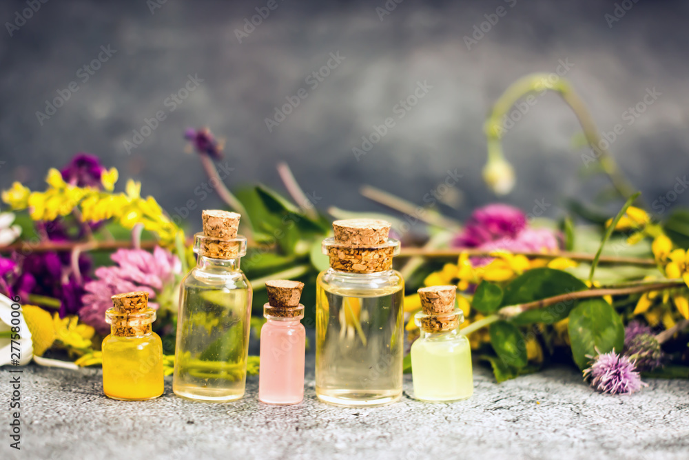 Transparent bottle with cork stopper with yellow oil on a background of wildflowers Transparent bottle with cork stopper with yellow oil on a background of wildflowers