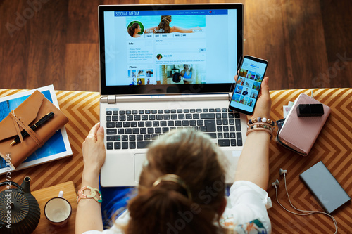 Принти на полотні young housewife checking social media on laptop and smartphone