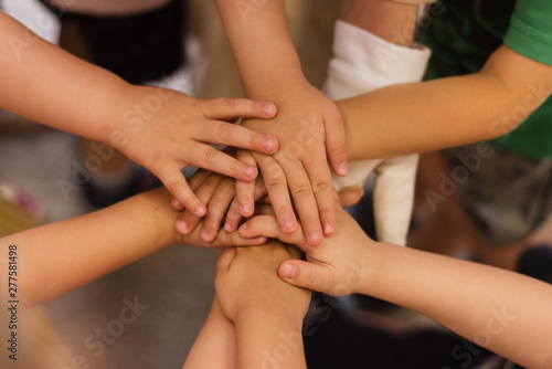 Children's hands piled on top of each other. Children's team and team building among the little guys