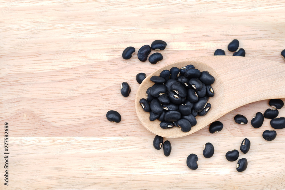 Close-up Raw black beans in a wooden spoon on wooden background, top view. Close-up Raw black beans in a wooden spoon on wooden background, top view.