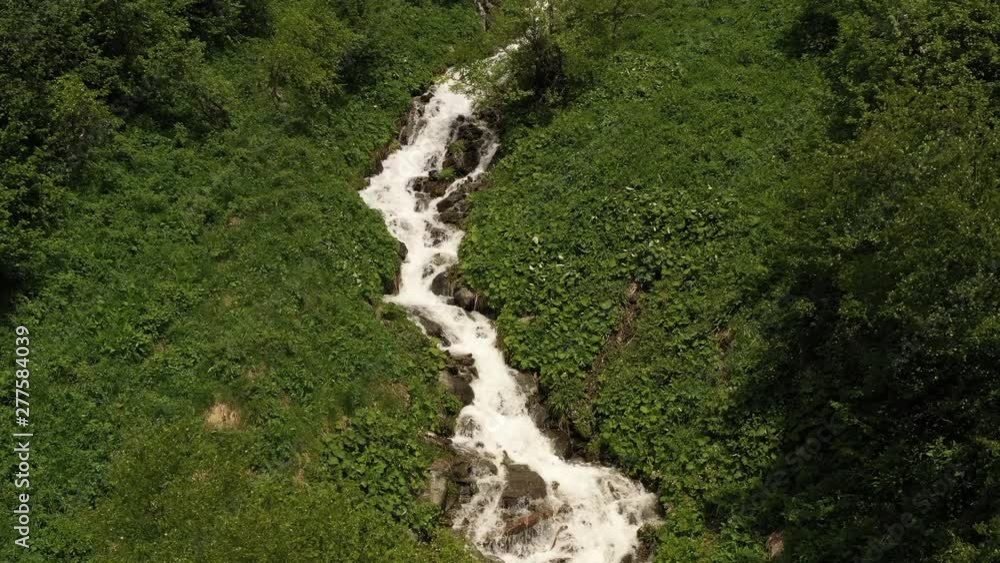 Flight over fast mountain river actively overcoming rocky rapids. Hiking trail along stream. Tourist destination magnificent pine forest among beautiful wooded hill. Adventure lifestyle. Aerial view Flight over fast mountain river actively overcoming rocky rapids. Hiking trail along stream. Tourist destination magnificent pine forest among beautiful wooded hill. Adventure lifestyle. Aerial view
