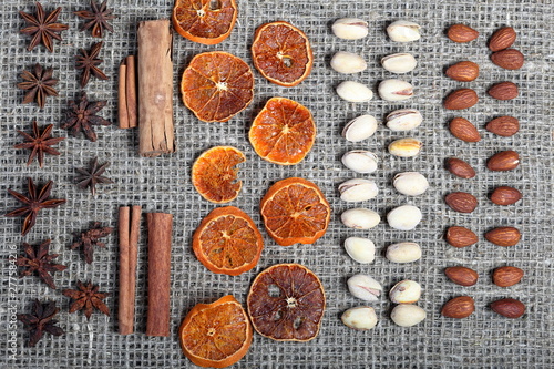 Dried orange slices, cinnamon and anise for decoration. Also pistachios and almonds are laid out in rows on coarse linen fabric.