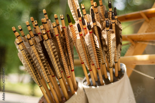 Many handcrafted arrows in a brown leather quiver full with arrows in crafted in medieval style, each arrow with different brown color on the feather. Close up, selective focus