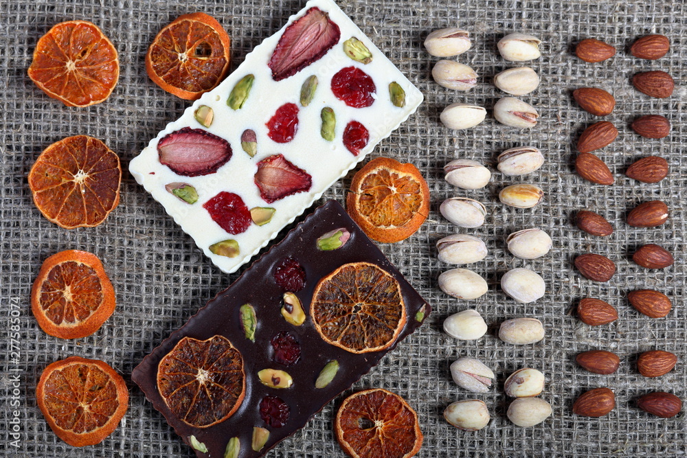 Dried orange slices, pistachios and almonds are lined up in rough linen fabric. Dark and white chocolate decorated with dried fruit. Dried orange slices, pistachios and almonds are lined up in rough linen fabric. Dark and white chocolate decorated with dried fruit.