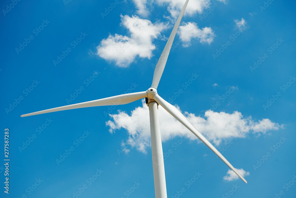 Fototapeta premium Electricity wind generator on bright cloudy sky background - wind energy and technology concept