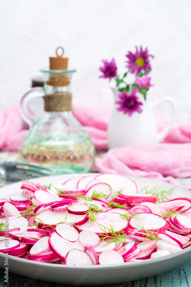 Fresh salad of radish and dill on a plate on a wooden table