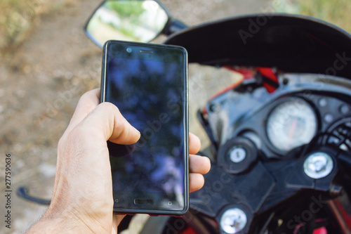 biker riding motorbike and holding smart phone