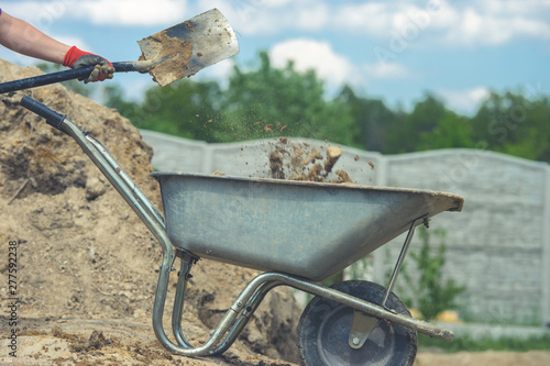 Foto Digging with a shovel. Throwing the soil into a wheelbarrow