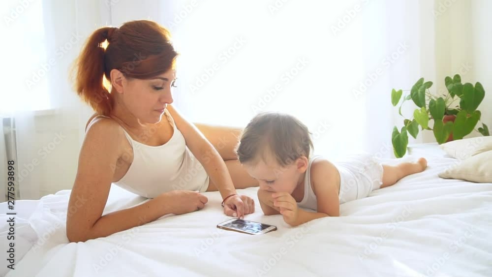 Mom and son watching smartphone in bedroom Mom and son watching smartphone in bedroom
