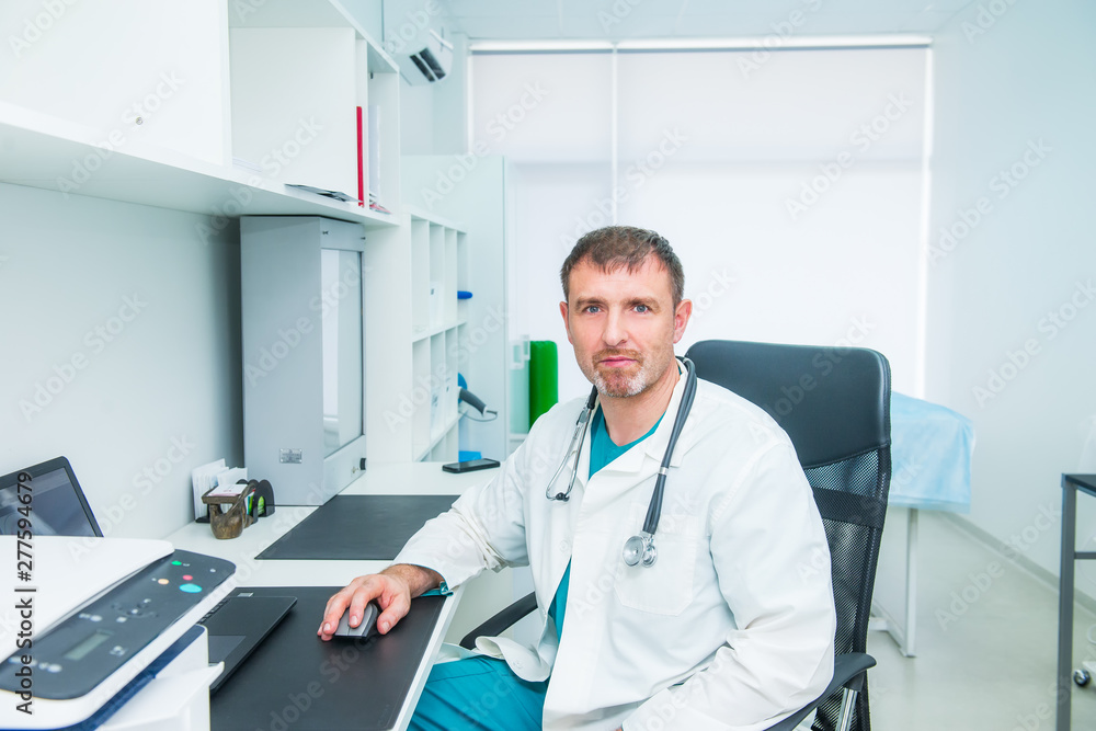 Portrait of male mature doctor feeling confident in himself while sitting on his working place and looking at camera. Medicine and health concept. Occupation. Copy space. Portrait of male mature doctor feeling confident in himself while sitting on his working place and looking at camera. Medicine and health concept. Occupation. Copy space.