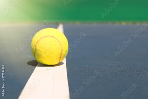 Yellow tennis ball lies on the white line of the court. Close up © makedonski2015
