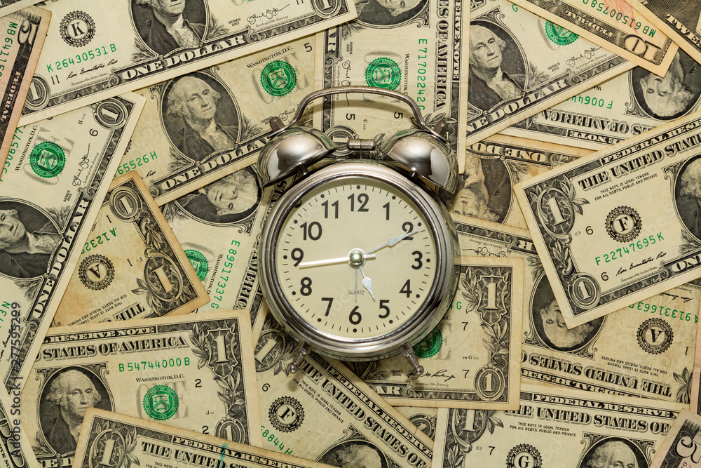 Alarm clock on carpet of dollar bills, time is money. Alarm clock on carpet of dollar bills, time is money.
